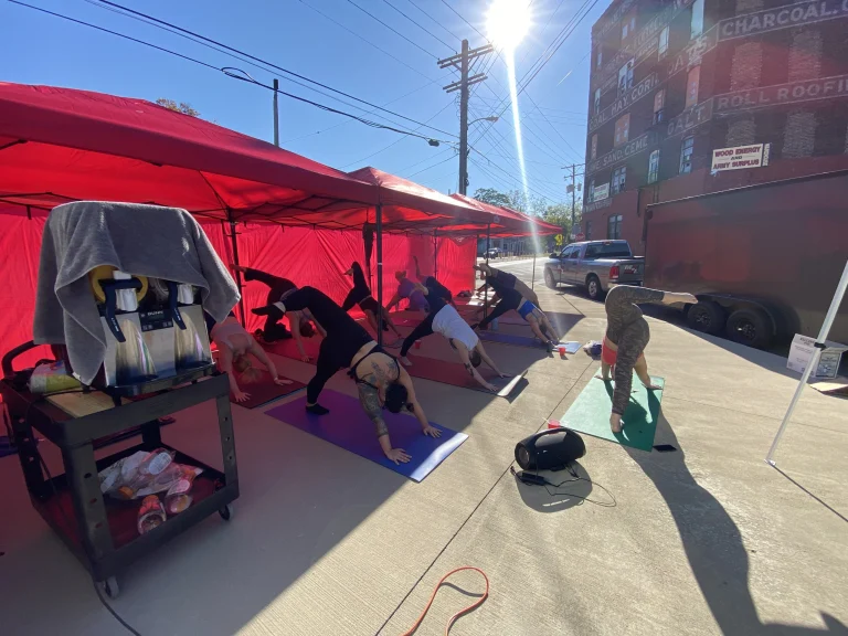 An outdoor yoga class under red tents