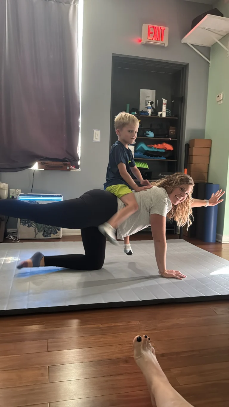 Ivy in tabletop pose with a child riding on her back