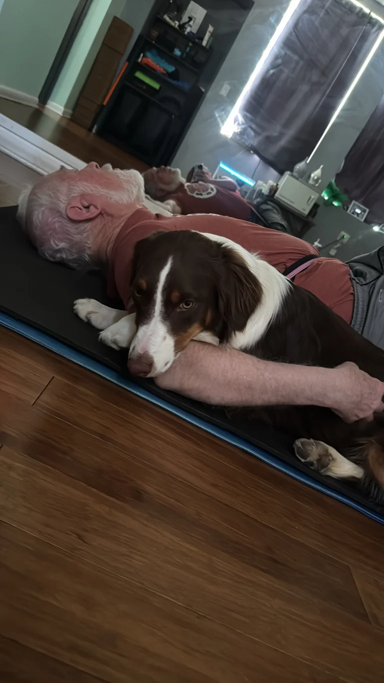 A student resting on his mat with the studio dog