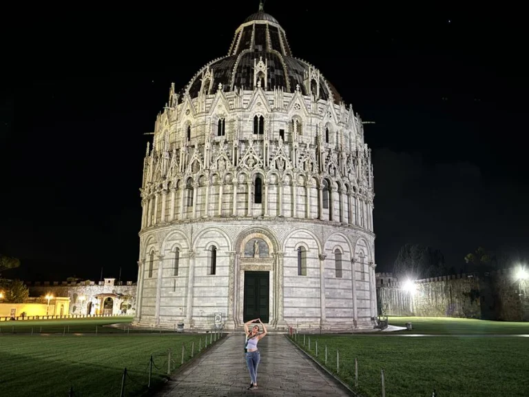 Ivy in a side bend in front of the floodlit Pisa baptistery at night